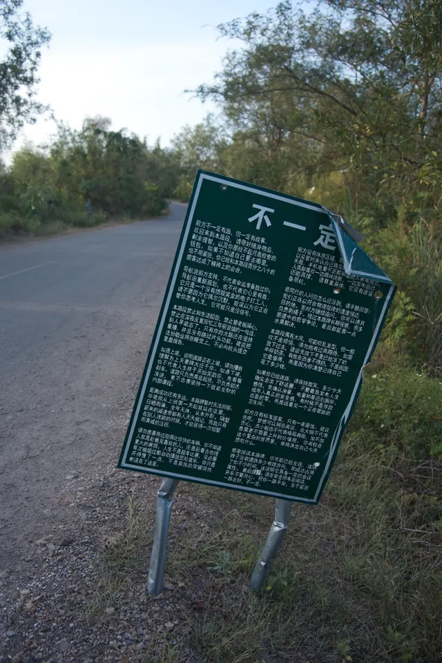 Photo of a bent roadside sign covered in dense humorous Chinese text, generated by MOSS-Image-Base